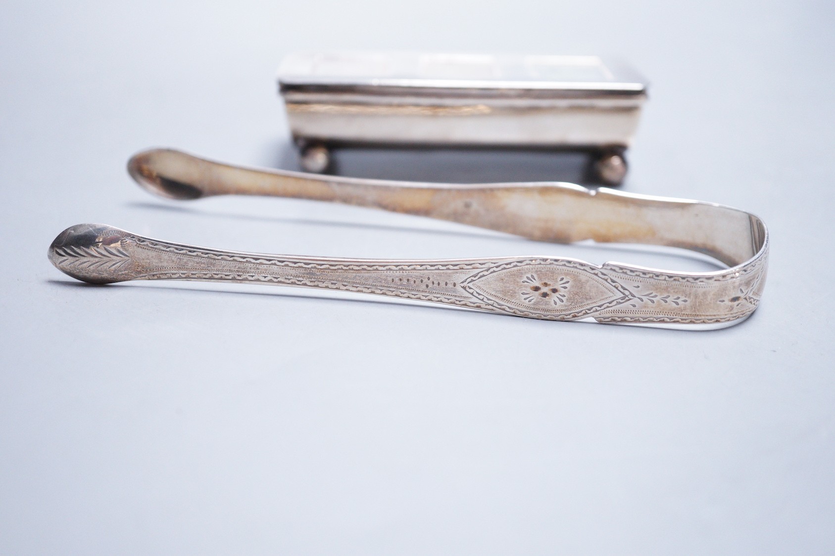 A late Victorian silver triple compartment stamp box, James Deakin & Sons, Birmingham, 1899, 88mm and two pairs of silver sugar tongs including Georgian.